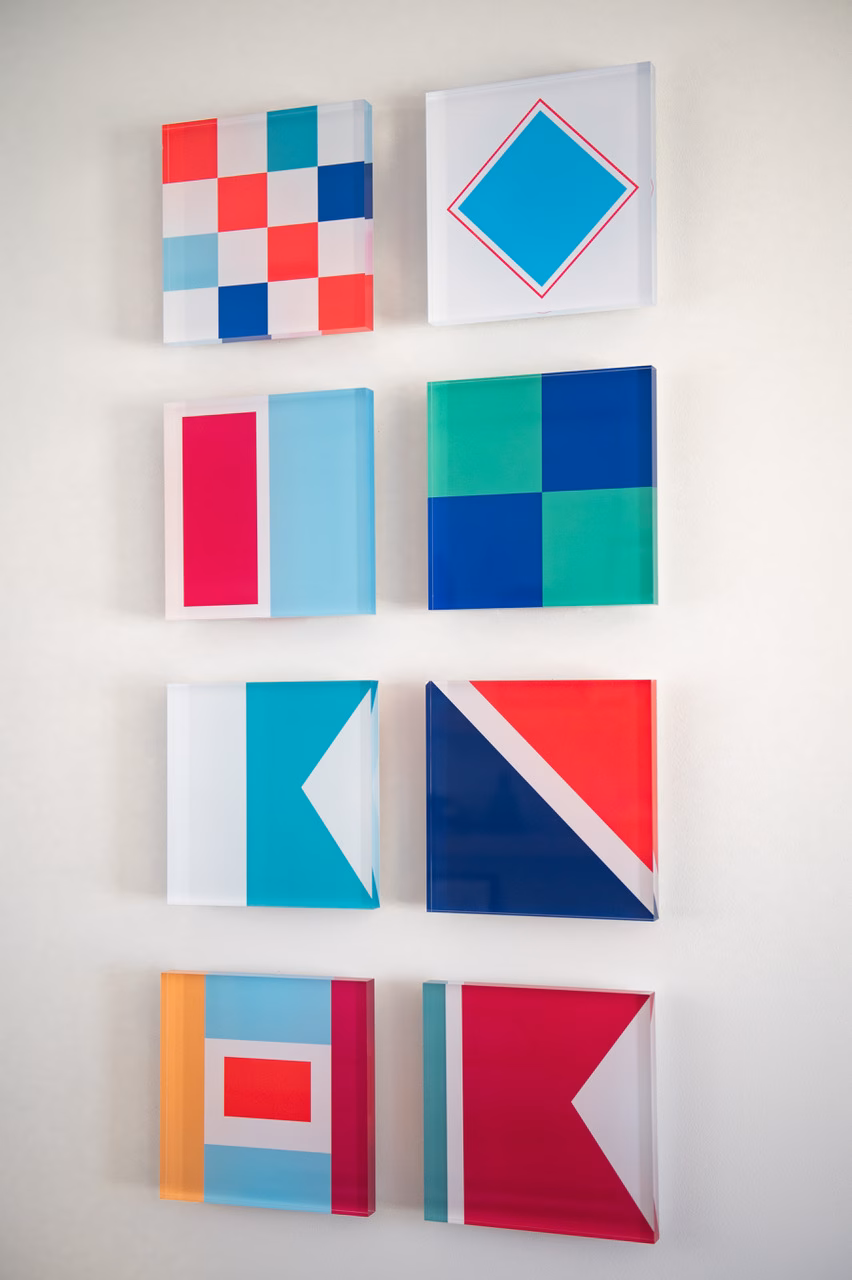 Nautical flag inspired artworks that are minimal in style with bold contemporary colors shown in three dimension hanging on a wall